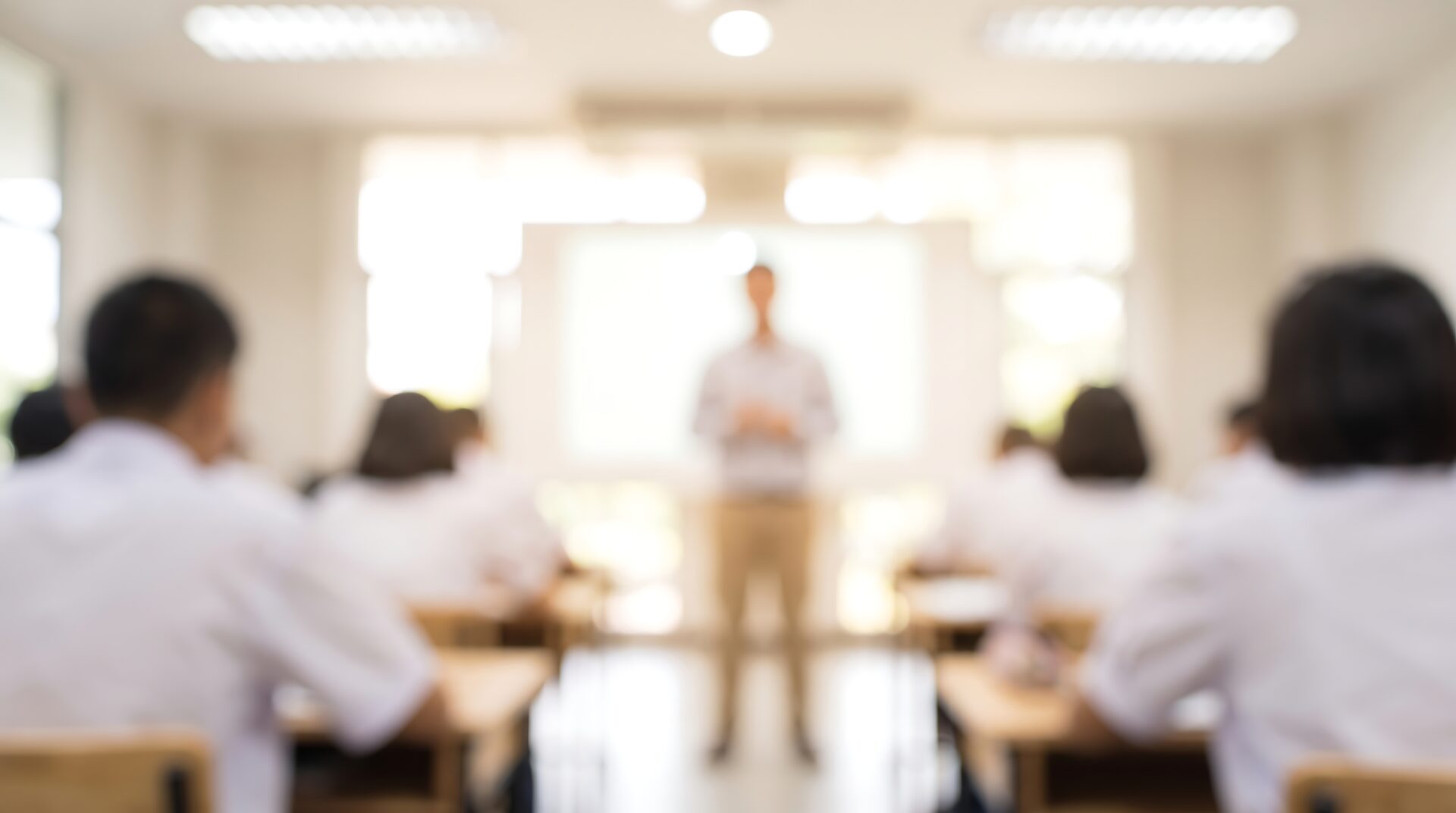 Blurred teacher standing in front of students in classroom during university lecture for academic success and education concepts in professional training or teaching environments